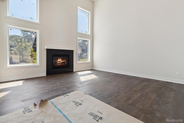 2911 Walsh Dr, Rochester Hills, MI 48309 - unfurnished living room featuring a glass covered fireplace, dark wood-type flooring, baseboards, and a towering ceiling