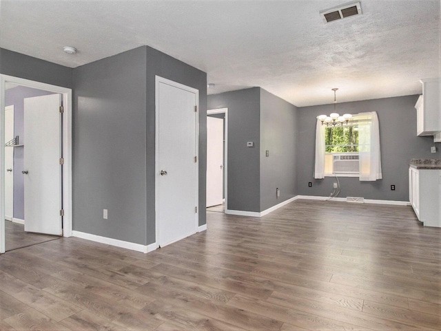 7929 N 48th St, Augusta, MI 49012 - unfurnished living room with dark wood finished floors, a textured ceiling, a chandelier, baseboards, and cooling unit