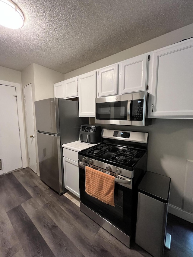 6530 Blue Lake Rd, Twin Lake, MI 49457 - kitchen with appliances with stainless steel finishes, a textured ceiling, dark wood-style flooring, white cabinetry, and light countertops