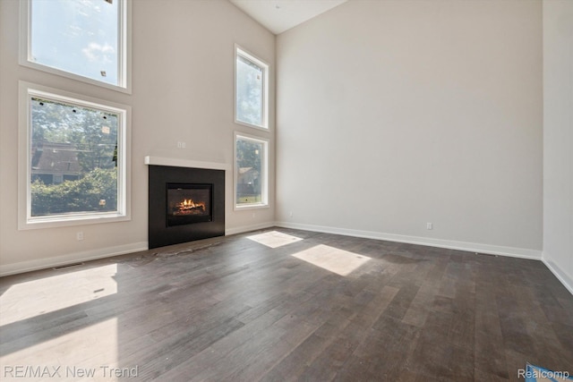 2921 Walsh Dr, Rochester Hills, MI 48309 - unfurnished living room featuring dark wood-style floors, a glass covered fireplace, baseboards, and a high ceiling