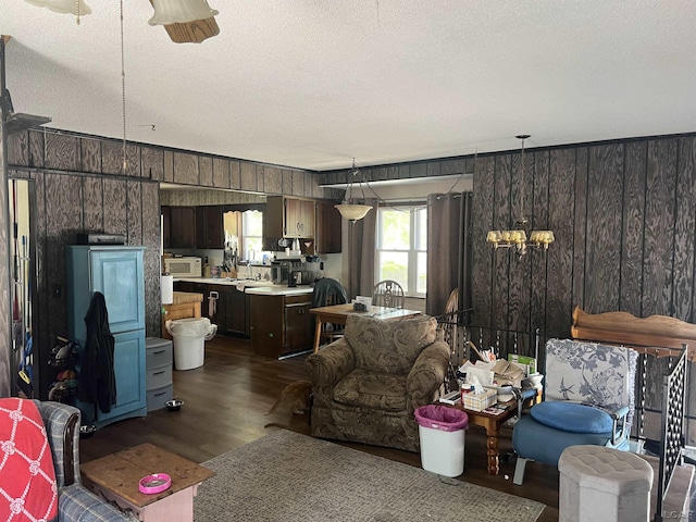 760 W Michigan Ave, Adrian, MI 49221 - living room with wood walls, a textured ceiling, dark wood finished floors, and a chandelier
