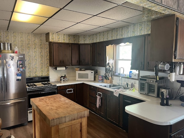 760 W Michigan Ave, Adrian, MI 49221 - kitchen with black appliances, wallpapered walls, dark wood-style flooring, a drop ceiling, and a center island