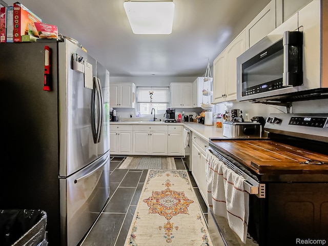 1468 Ruby Ave, Rochester Hills, MI 48309 - kitchen featuring stainless steel appliances, a sink, white cabinetry, and dark tile patterned flooring