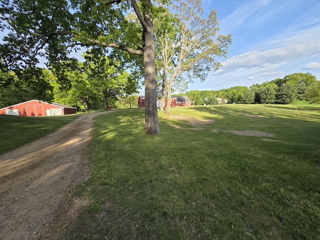 6541 S 6th St, Kalamazoo, MI 49008 - view of grassy yard featuring a garage, an outbuilding, an outdoor structure, dirt driveway, and view of scattered trees