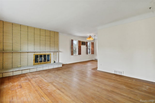 13128 Talbot Ave, Huntington Woods, MI 48070 - unfurnished living room with a chandelier, wood finished floors, baseboards, and a brick fireplace