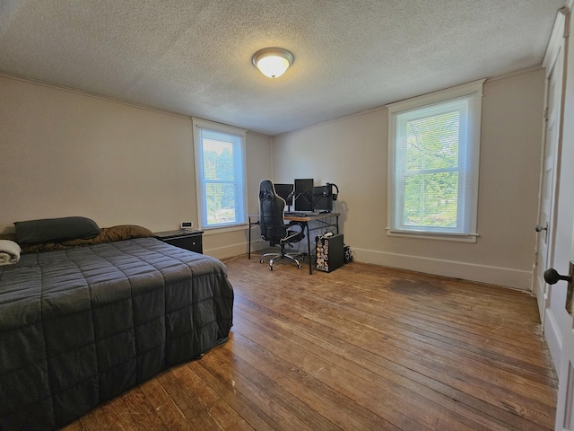1114 E Michigan Ave, Albion, MI 49224 - bedroom featuring a desk, hardwood / wood-style floors, a textured ceiling, and baseboards
