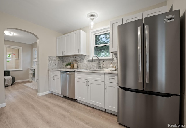 28517 Aberdeen St, Southfield, MI 48076 - kitchen featuring stainless steel appliances, a sink, arched walkways, backsplash, and light wood-style floors