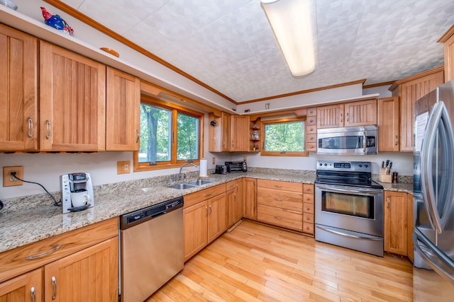 7945 W Royal Rd, Canadian Lakes, MI 49346 - kitchen featuring stainless steel appliances, crown molding, light stone counters, a sink, and light wood-type flooring