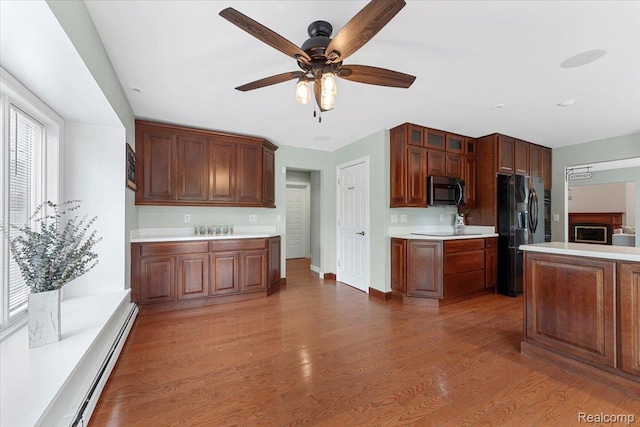 10161 N Loma Cir, Grosse Ile, MI 48138 - kitchen with black fridge, light countertops, a ceiling fan, glass insert cabinets, and light wood-style floors