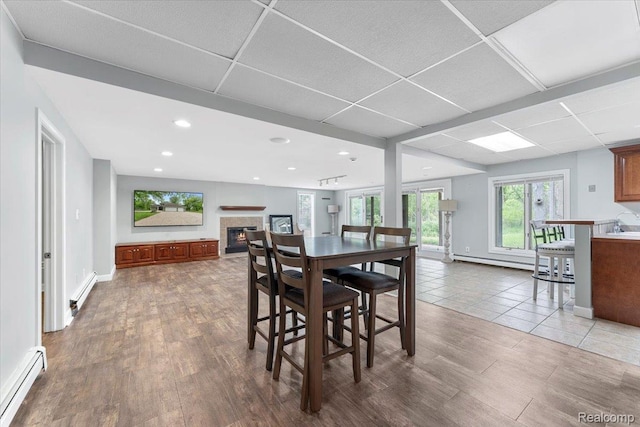 10161 N Loma Cir, Grosse Ile, MI 48138 - dining room featuring a baseboard heating unit, a glass covered fireplace, wood finished floors, a baseboard radiator, and recessed lighting