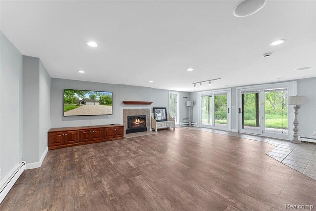 10161 N Loma Cir, Grosse Ile, MI 48138 - unfurnished living room with a baseboard radiator, a tiled fireplace, dark wood finished floors, and recessed lighting