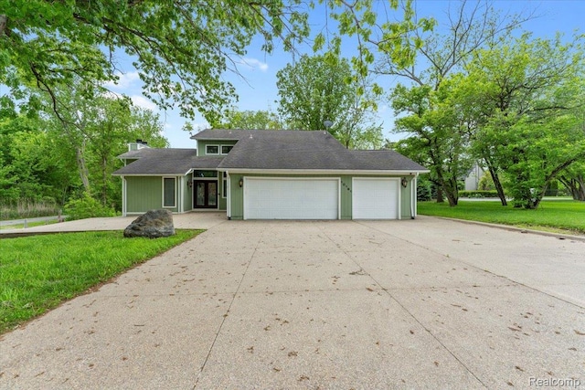 10161 N Loma Cir, Grosse Ile, MI 48138 - mid-century inspired home featuring a garage, concrete driveway, a front lawn, and french doors