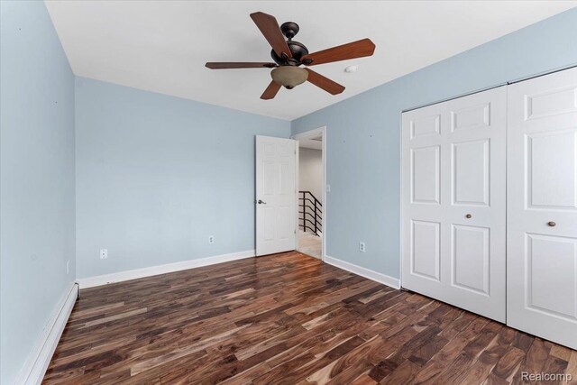 10161 N Loma Cir, Grosse Ile, MI 48138 - unfurnished bedroom featuring dark wood-style floors, a baseboard heating unit, baseboards, and a closet