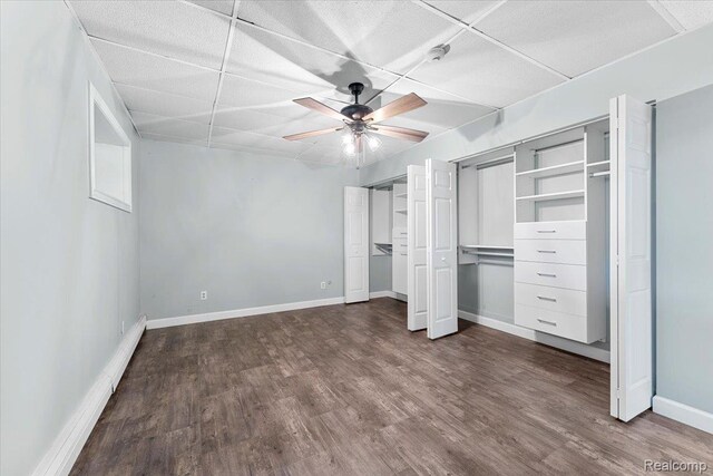 10161 N Loma Cir, Grosse Ile, MI 48138 - unfurnished bedroom with dark wood-style floors, multiple closets, baseboards, a ceiling fan, and a drop ceiling