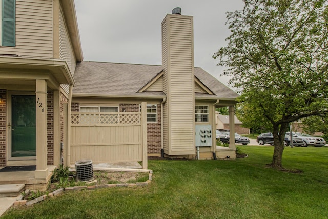 128 Commons Cir, Saline, MI 48176 - rear view of house with brick siding, a chimney, central air condition unit, and roof with shingles