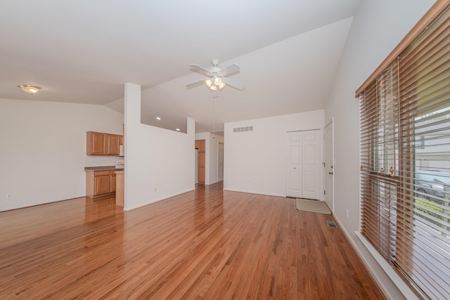 128 Commons Cir, Saline, MI 48176 - unfurnished living room with vaulted ceiling, ceiling fan, and light wood-style flooring