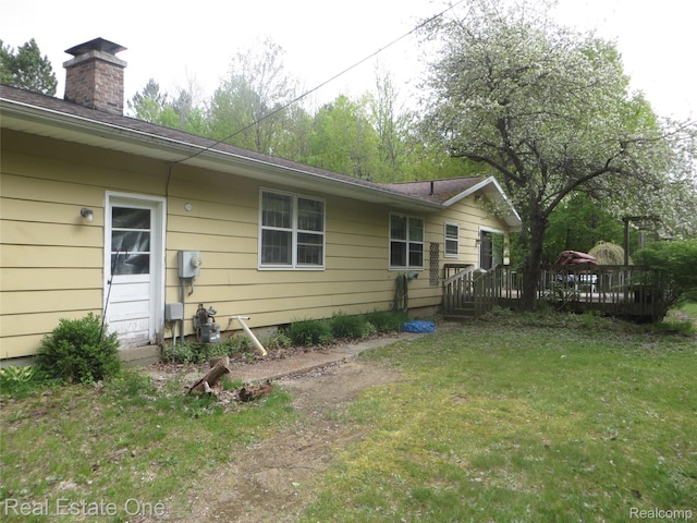 4072 M 55, Cadillac, MI 49601 - rear view of house with a deck, a yard, and a chimney