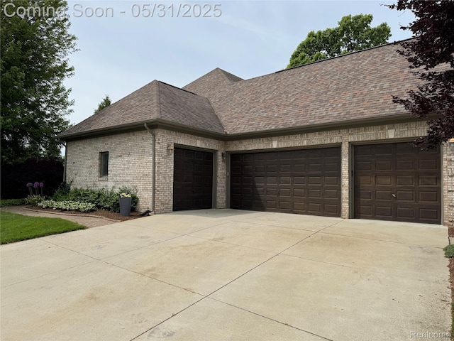 7348 William Dr, Shelby Twp, MI 48316 - view of side of property featuring an attached garage, driveway, a shingled roof, and brick siding
