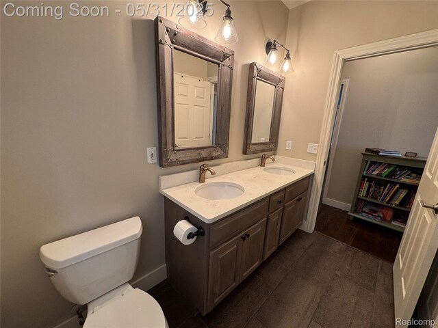 7348 William Dr, Shelby Twp, MI 48316 - bathroom with toilet, double vanity, wood finished floors, and baseboards