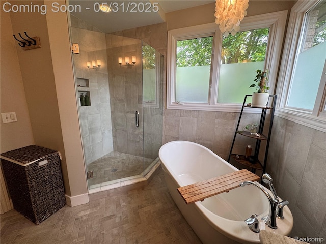 7348 William Dr, Shelby Twp, MI 48316 - bathroom featuring healthy amount of natural light, a freestanding tub, a shower stall, a chandelier, and tile walls