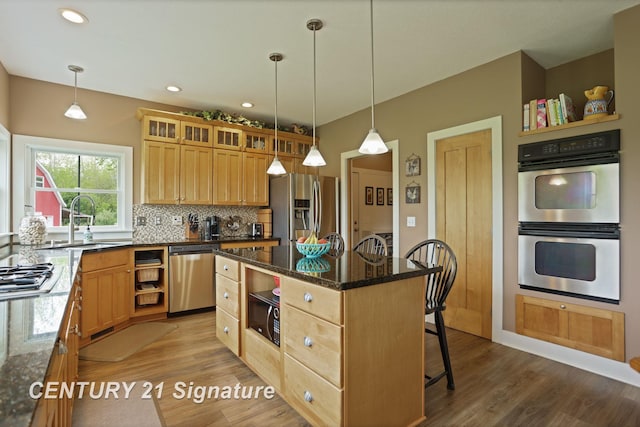 12751 Wilkinson Rd, Freeland, MI 48623 - kitchen featuring appliances with stainless steel finishes, a sink, dark stone countertops, tasteful backsplash, and a center island