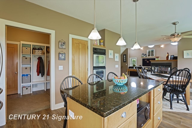 12751 Wilkinson Rd, Freeland, MI 48623 - kitchen with stainless steel double oven, dark wood-type flooring, black microwave, a glass covered fireplace, and ceiling fan