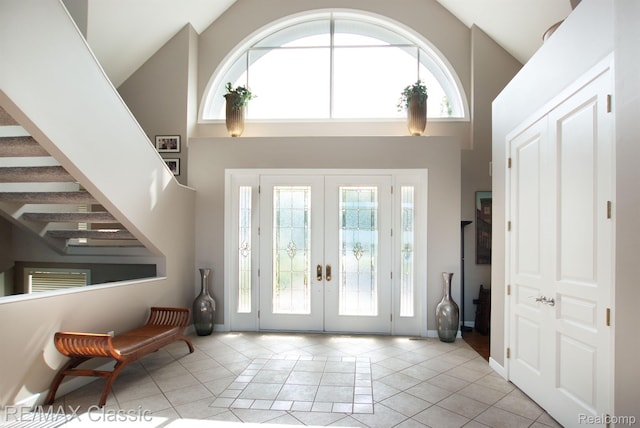 826 Wolverine Dr, Wolverine Lake, MI 48390 - foyer with high vaulted ceiling, french doors, light tile patterned floors, stairs, and baseboards