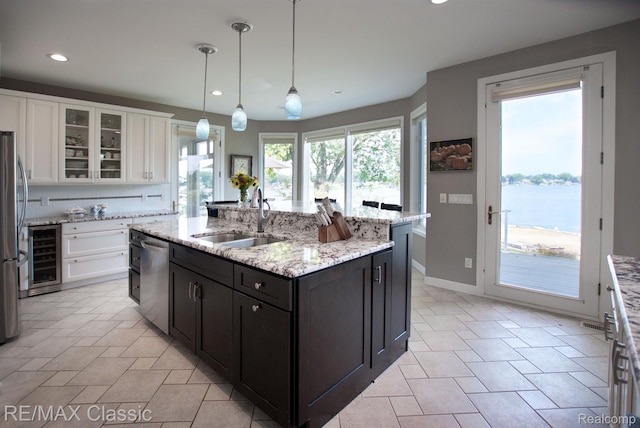 826 Wolverine Dr, Wolverine Lake, MI 48390 - kitchen with appliances with stainless steel finishes, a sink, wine cooler, white cabinetry, and an island with sink