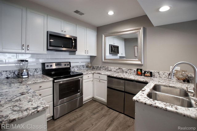 826 Wolverine Dr, Wolverine Lake, MI 48390 - kitchen featuring stainless steel appliances, a sink, dark wood-style floors, white cabinets, and light stone countertops