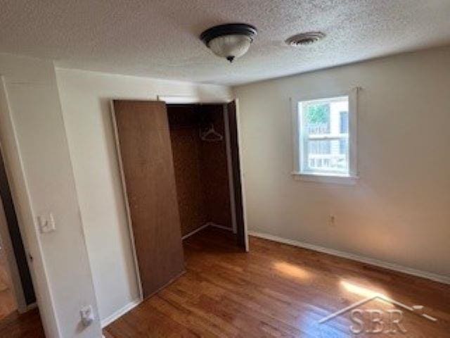 4411 W Michigan Ave, Saginaw, MI 48638 - unfurnished bedroom with a textured ceiling, wood finished floors, and a closet