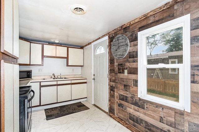 4411 W Michigan Ave, Saginaw, MI 48638 - kitchen with appliances with stainless steel finishes, wooden walls, light countertops, light marble finish floors, and white cabinetry