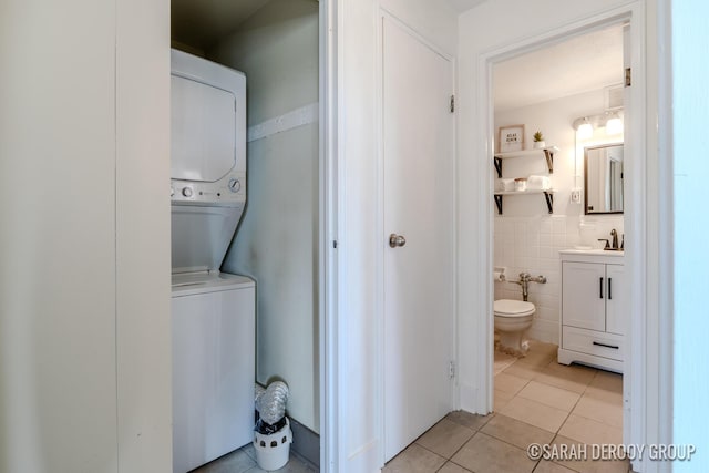 505 Cherry St SE Unit 512, Grand Rapids, MI 49503 - washroom featuring stacked washing machine and dryer, light tile patterned flooring, a sink, and tile walls