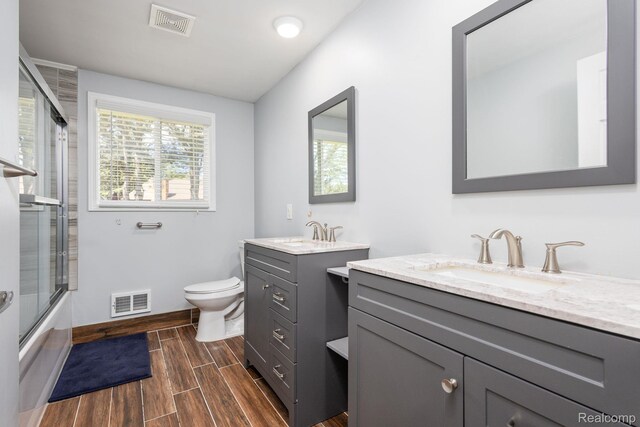667 Heritage Ln, Rochester, MI 48309 - full bathroom with two vanities, baseboards, wood finish floors, toilet, and combined bath / shower with glass door