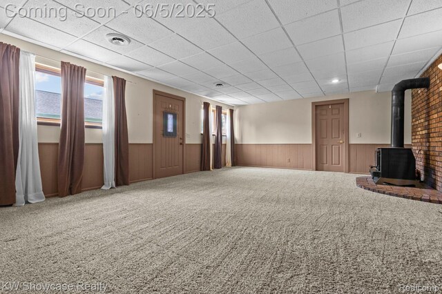 3430 Woodvalley Dr, Lapeer, MI 48446 - unfurnished living room featuring wainscoting, a wood stove, plenty of natural light, a paneled ceiling, and carpet flooring