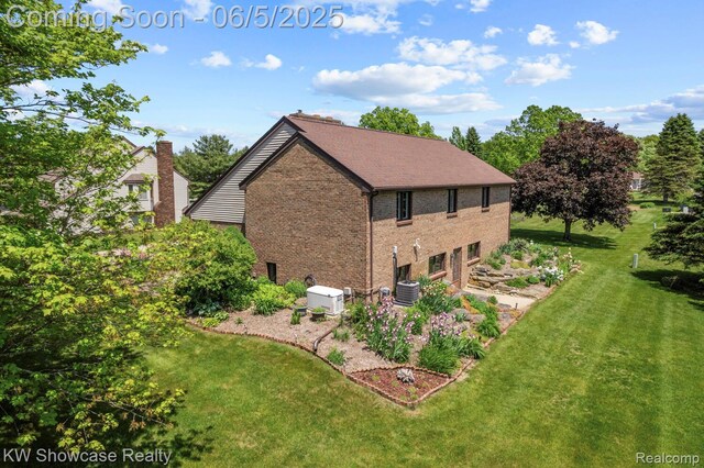 3430 Woodvalley Dr, Lapeer, MI 48446 - view of property exterior featuring a lawn, brick siding, a garage, and central AC