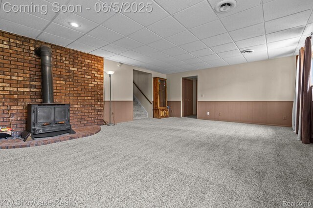 3430 Woodvalley Dr, Lapeer, MI 48446 - unfurnished living room with stairway, a wainscoted wall, carpet flooring, a wood stove, and a paneled ceiling
