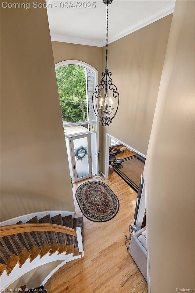 3448 Circle Dr, Commerce Twp, MI 48382 - stairs featuring wood finished floors, ornamental molding, and a chandelier