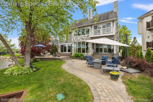 3448 Circle Dr, Commerce Twp, MI 48382 - back of property featuring a balcony, a patio, stone siding, a chimney, and a lawn
