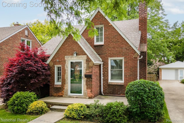 2029 Hubbell St, Dearborn, MI 48128 - tudor home with roof with shingles, a chimney, brick siding, an outdoor structure, and a garage