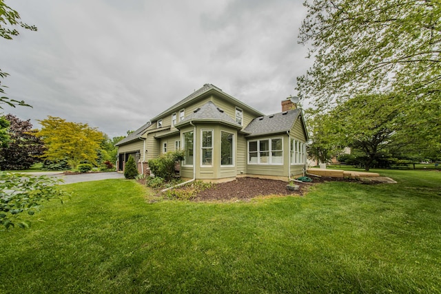 9117 Cambridge Dr, Saline, MI 48176 - back of property with a chimney, driveway, a lawn, a garage, and roof with shingles