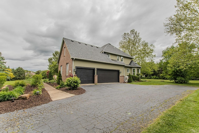 9117 Cambridge Dr, Saline, MI 48176 - view of side of home with brick siding, driveway, a shingled roof, a garage, and a lawn