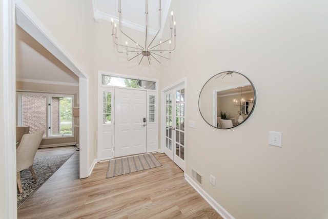 9117 Cambridge Dr, Saline, MI 48176 - entrance foyer featuring ornamental molding, a chandelier, baseboards, a towering ceiling, and light wood-type flooring