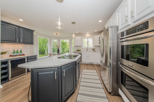 9117 Cambridge Dr, Saline, MI 48176 - kitchen featuring wine cooler, appliances with stainless steel finishes, white cabinetry, backsplash, and a sink