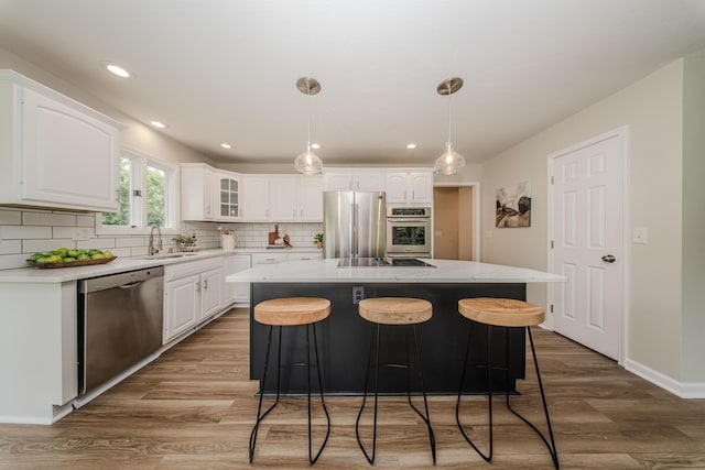 9117 Cambridge Dr, Saline, MI 48176 - kitchen featuring stainless steel appliances, a sink, light wood-style flooring, white cabinetry, and tasteful backsplash
