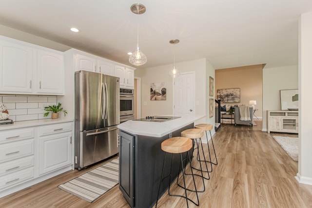 9117 Cambridge Dr, Saline, MI 48176 - kitchen with stainless steel appliances, white cabinets, light wood finished floors, a breakfast bar, and recessed lighting