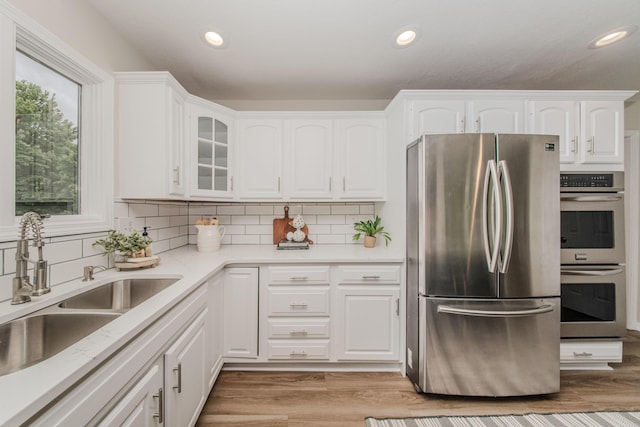 9117 Cambridge Dr, Saline, MI 48176 - kitchen with appliances with stainless steel finishes, a sink, white cabinets, glass insert cabinets, and decorative backsplash