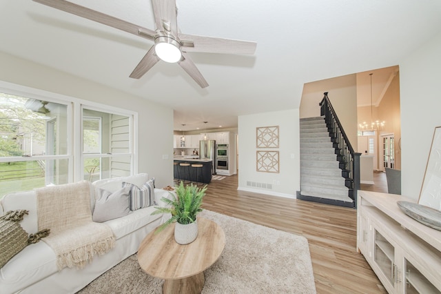 9117 Cambridge Dr, Saline, MI 48176 - living room featuring light wood-style floors, stairway, a chandelier, and baseboards