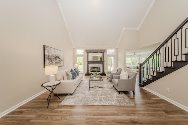 9117 Cambridge Dr, Saline, MI 48176 - living room with crown molding, high vaulted ceiling, stairway, a stone fireplace, and baseboards