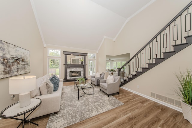 9117 Cambridge Dr, Saline, MI 48176 - living room with high vaulted ceiling, ornamental molding, a stone fireplace, stairway, and wood finished floors