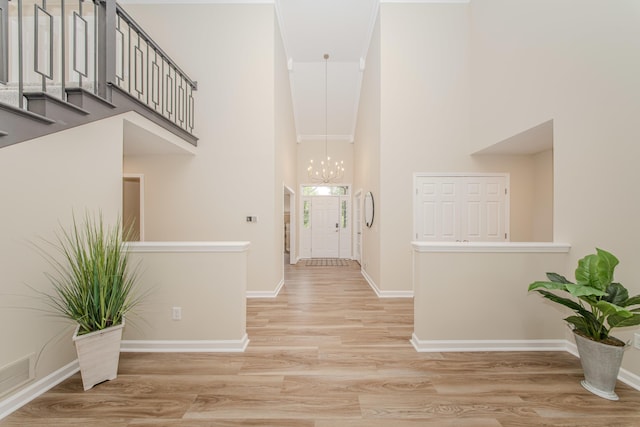 9117 Cambridge Dr, Saline, MI 48176 - entryway with a towering ceiling, a chandelier, light wood-style flooring, baseboards, and stairs